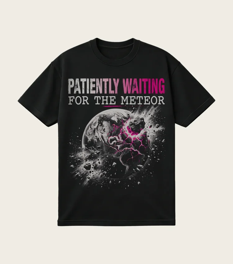 Patiently Waiting for the Meteor printed on a black t-shirt, laid flat